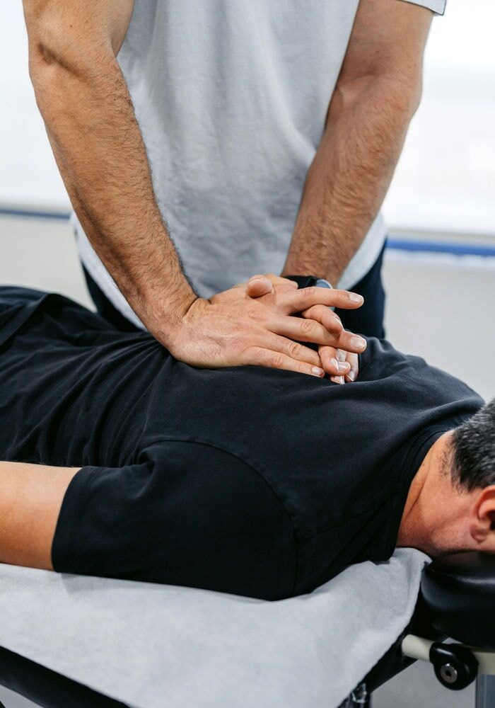 Chiropractor aligning patient’s spine during back adjustment session.
