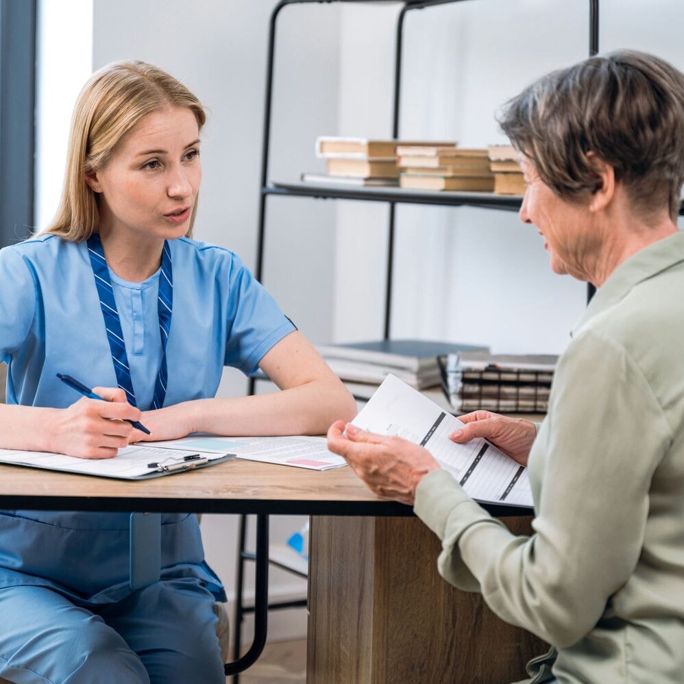 Clinician taking history and reviewing a treatment plan with a patient across the desk.