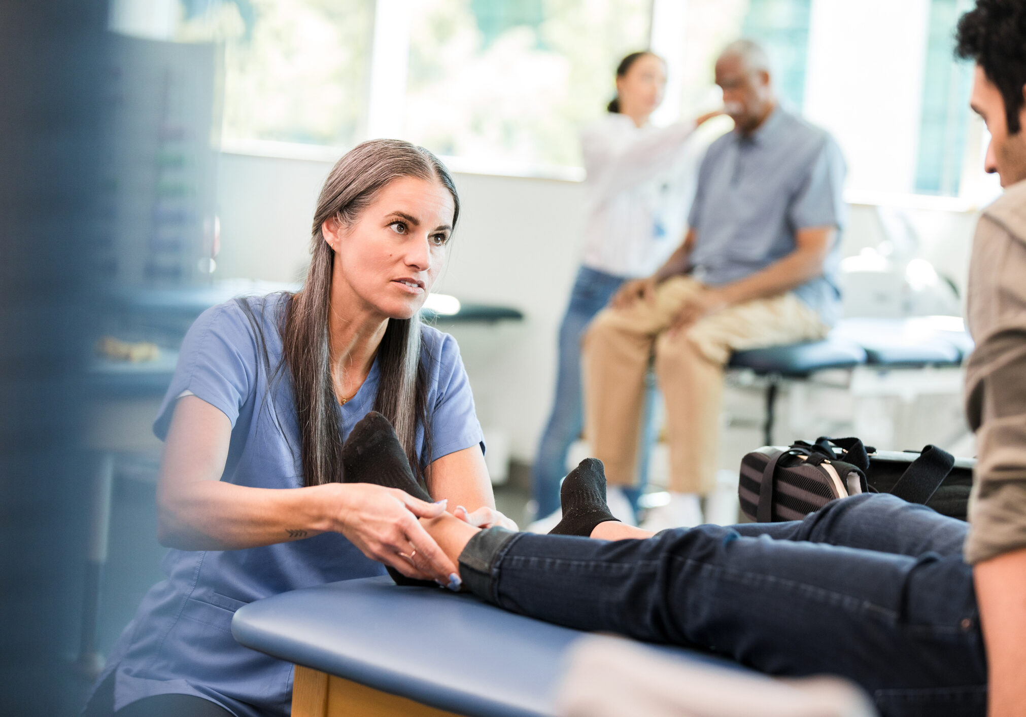 Female physical therapist examining a patient's foot during a session. Healthcare and medicine.