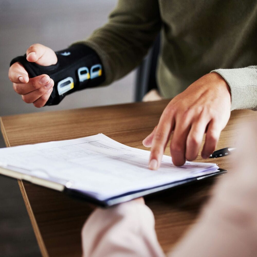 Person wearing a wrist brace reviewing documents during an independent medical evaluation